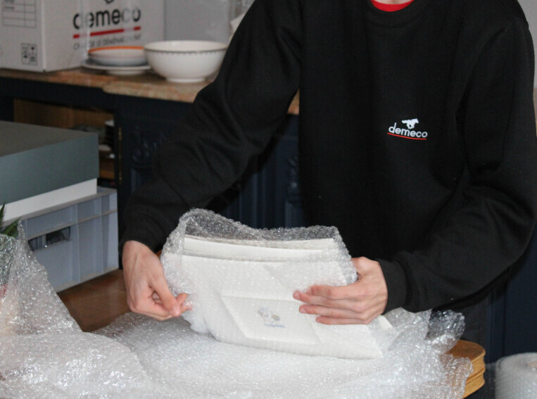 Personnel de Déméco en train d'emballer des assiettes dans du papier bulle