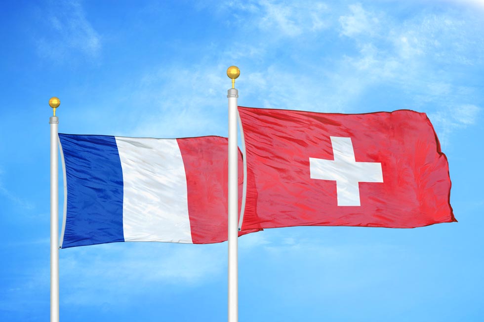 France et Suisse deux drapeaux sur les mâts et le ciel nuageux bleu