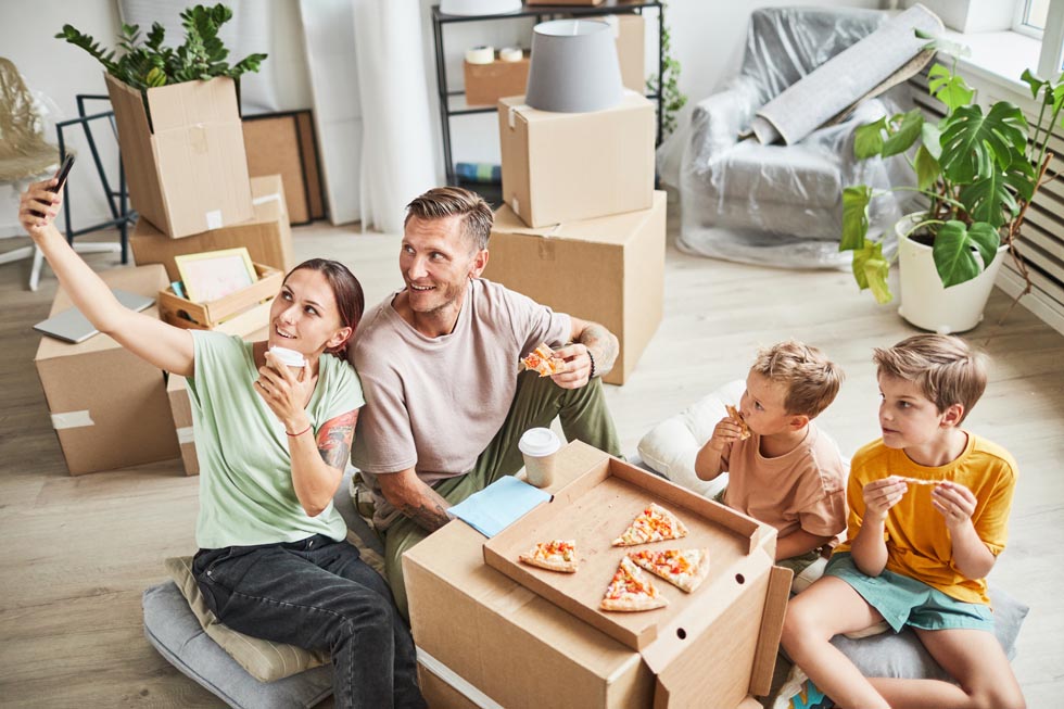 Famille en train de manger pendant leur déménégaement au milieu des cartons